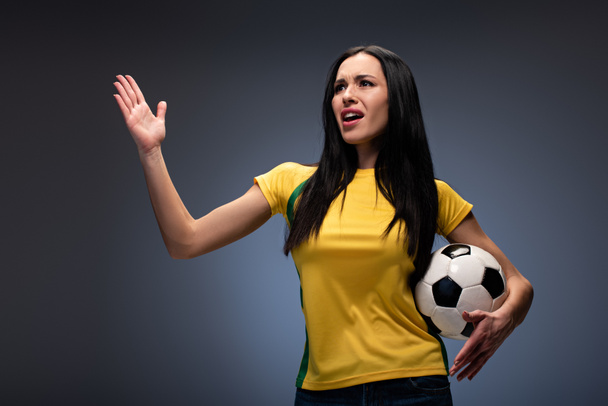 beautiful angry girl holding football ball on grey - Φωτογραφία, εικόνα