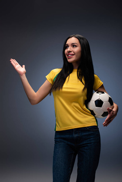beautiful surprised football fan holding ball on grey - 写真・画像