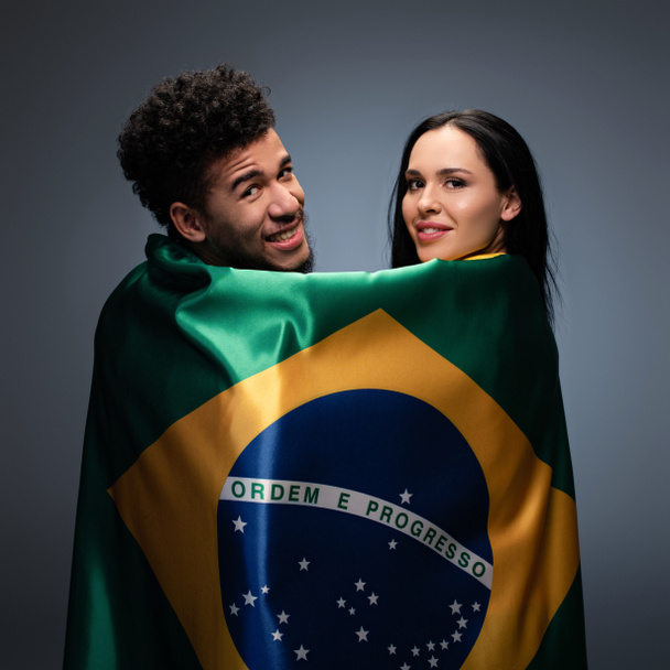 casal multicultural de fãs de futebol positivo com bandeira do brasil em cinza
 - Foto, Imagem