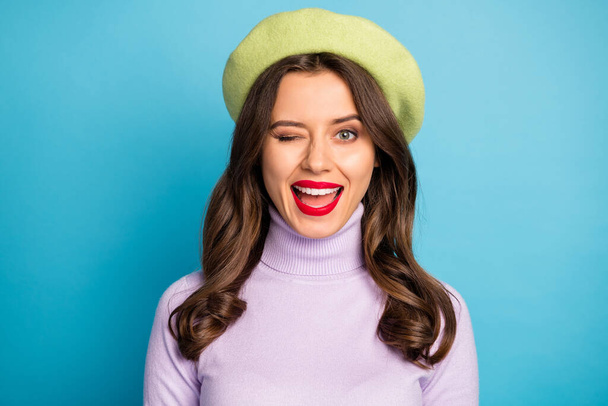 Closeup photo of pretty lady good mood red lips coquettish person blinking one eye see handsome guy wear green beret hat purple turtleneck isolated blue color background - Photo, Image