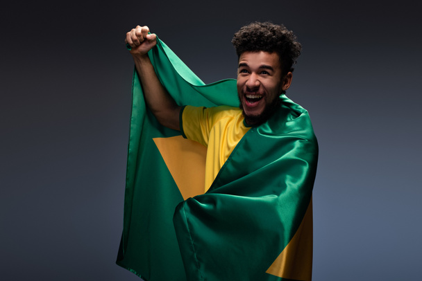 sorridente fã de futebol americano africano envolto em bandeira brasileira em cinza
 - Foto, Imagem
