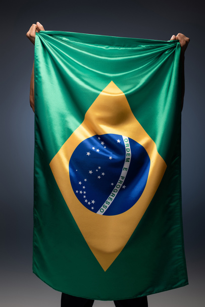 back view of football fan holding brazilian flag on grey - Foto, immagini