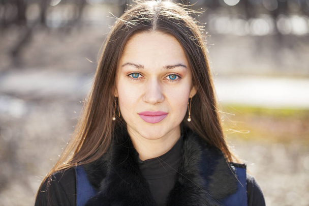 Close up, Portrait of a young beautiful woman in blue coat in spring park - Photo, image