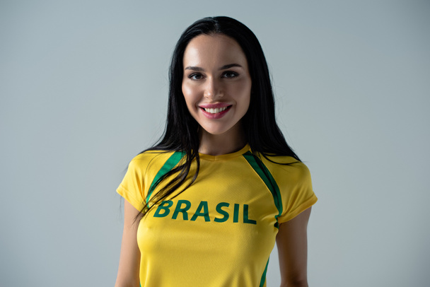 sorridente fã de futebol feminino em camiseta amarela com sinal brasil isolado em cinza
  - Foto, Imagem