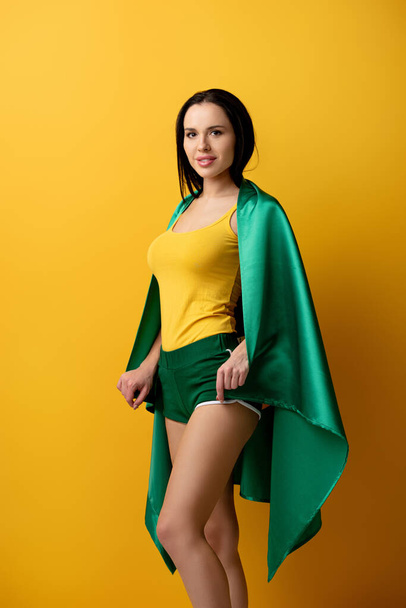 bela fã de futebol feminino em shorts segurando bandeira brasileira em amarelo
  - Foto, Imagem