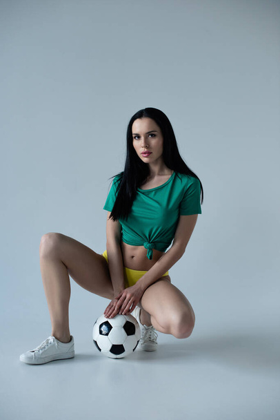 attractive sexy football fan posing with ball on grey - Foto, afbeelding