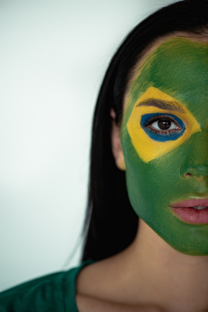 atractivo ventilador de fútbol femenino con bandera brasileña pintada en la cara en gris
 - Foto, Imagen