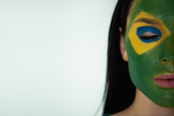 female football fan with closed eyes and painted brazilian flag on face isolated on grey - Photo, Image