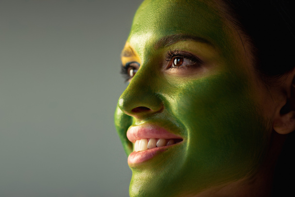 happy beautiful woman with painted brazilian flag on face  isolated on grey - Photo, Image