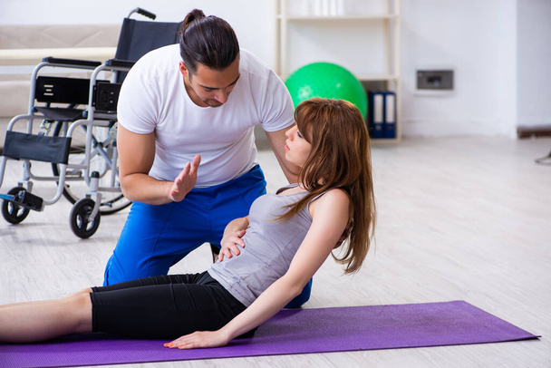 Mužský fyzioterapeut dělá cvičení se zraněnou ženou na podlaze - Fotografie, Obrázek