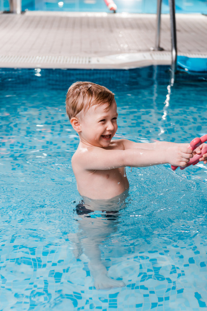 happy toddler kid playing with rubber toy in swimming pool  - Zdjęcie, obraz