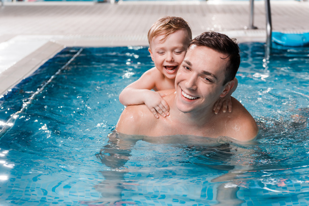 happy toddler kid and swim coach smiling in swimming pool  - Photo, Image