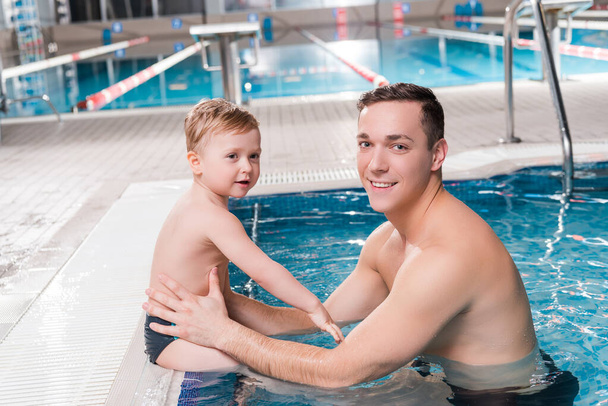 ευτυχισμένος εκπαιδευτής κολύμβησης και νήπιο παιδί κοντά στην πισίνα  - Φωτογραφία, εικόνα