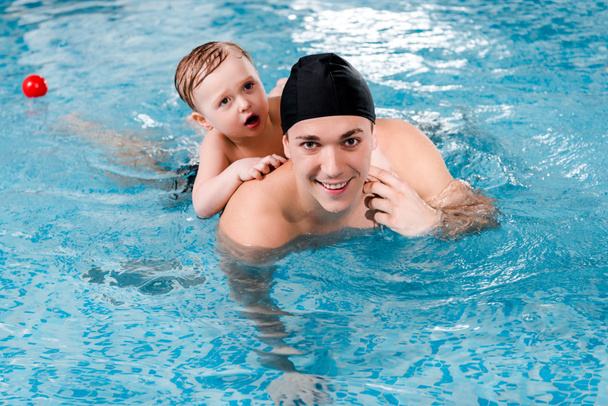 happy swim coach and toddler boy training in swimming pool  - Photo, Image