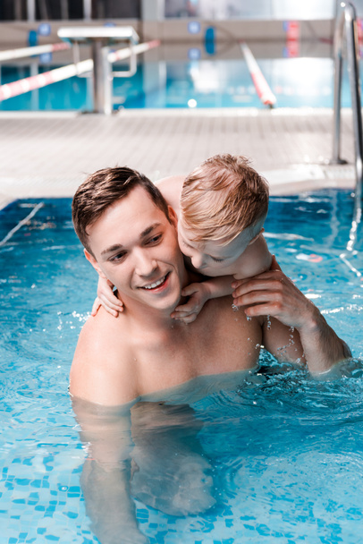 Niedlicher Kleinkind Junge umarmt glücklichen Schwimmtrainer im Schwimmbad  - Foto, Bild