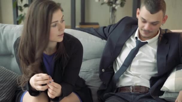 Young couple sitting on a couch and talking to a psychologist or doctor - Filmagem, Vídeo