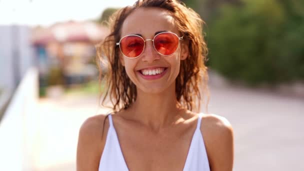 slow motion close up portrait of Beautiful young tanned woman in pink sunglasses posing on bay at seaside - Materiaali, video