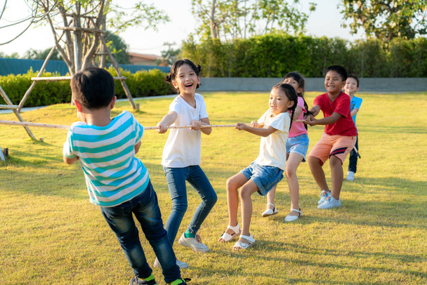 夏の日に市内公園の遊び場で綱引きをしたり、ロープを引っ張ったりしている幸せな若いアジアの子供たちのグループ。子供とレクリエーションの概念 - 写真・画像