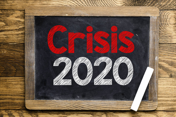 Crisis 2020 texto en una pizarra situada en una mesa de madera. Se avecina una crisis económica y económica debido al coronavirus imperante en todo el mundo. - Foto, imagen