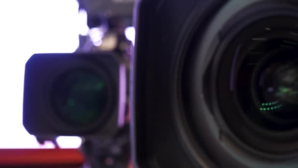 Close up of beautiful camera lens on white blurred background. Stock footage. Front element of a camera lens with beautiful color lights reflections. - Footage, Video