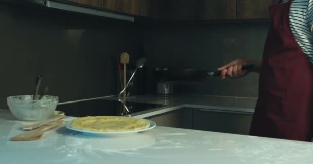 A young man is in his modern kitchen and is flipping pancakes - Filmati, video