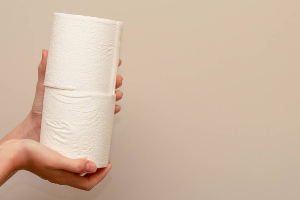 Закрыть руки, держащие два рулона туалетной бумаги на нейтральном фоне. Концепция дефицита и запасов
 - Фото, изображение