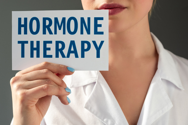 Vue agrandie d'un médecin tenant une carte avec lettrage hormonal isolé sur gris - Photo, image