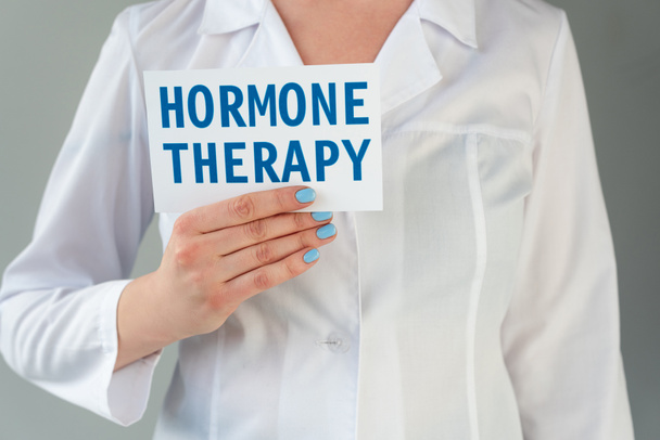 Vágott kilátás orvos fehér köpenyes holding kártya hormon terápiás betű izolált szürke - Fotó, kép