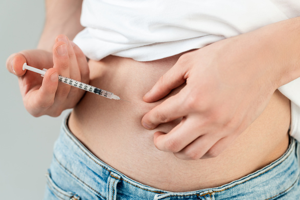 Cropped view of man doing hormonal injection in belly isolated on grey - Foto, Imagem