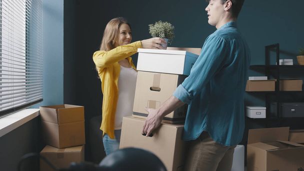 Happy couple moving in their new house, the man is carrying a heavy load of boxes - Fotoğraf, Görsel