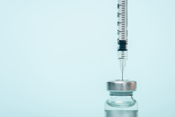 close-up zicht op potje hormonaal vaccin en spuit geïsoleerd op blauw - Foto, afbeelding