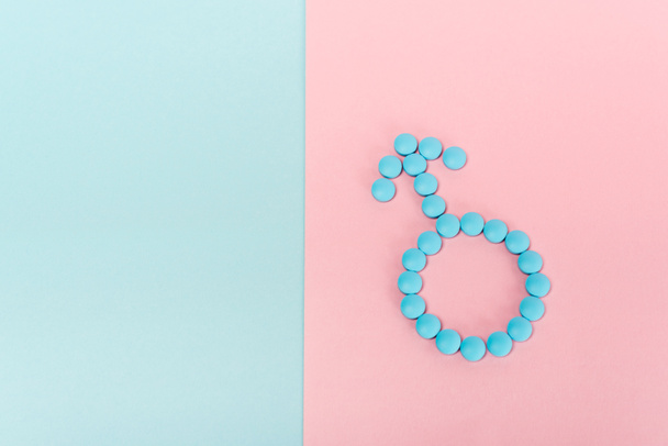 Вид зверху чоловічий знак з гормональних таблеток на синьо-рожевій поверхні
 - Фото, зображення