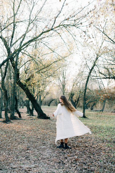 portré egy fiatal vonzó szőke lány világos fehér ruhában és fekete cipő között egy festői erdő - Fotó, kép
