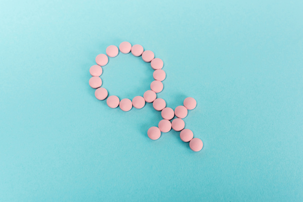 Magas szög kilátás a női jel a hormonális tabletták kék háttér - Fotó, kép