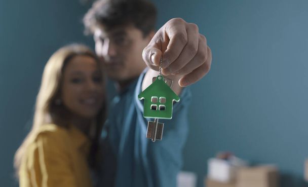 Happy couple holding house keys, they have bought their new house together - Photo, Image