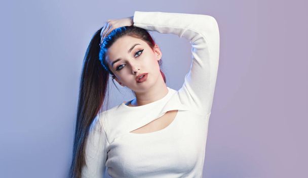portrait of cocky girl with long ponytail hair on studio background, young woman with rebellious character, fashion model - Foto, Imagem