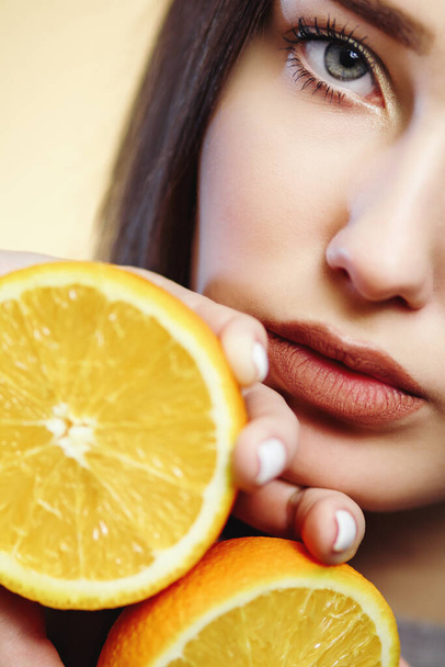 bright portrait of beautiful woman with orange halves, girl face with languid look, fashion model, concept fruits and healthy food - 写真・画像