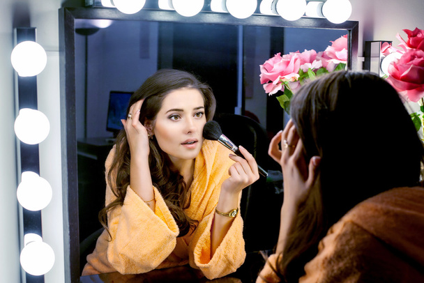 kobieta w pomarańczowe szaty robi jej makijaż i wathching w lustro - Zdjęcie, obraz