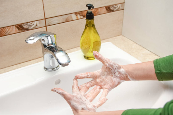 Lavarsi le mani con il sapone sotto il rubinetto con acqua - Foto, immagini