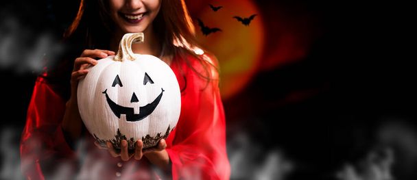Happy Halloween. Beautiful woman costume and holding pumpkin. Copy space on dark background. - Foto, afbeelding