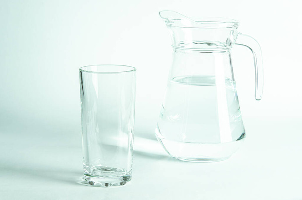 Pure clear water in a glass and jug stands on a white background. isolated - Photo, Image