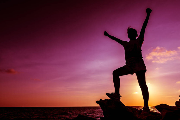 Silhouette de femme sportive sur la falaise au coucher du soleil, concept de succès - Photo, image