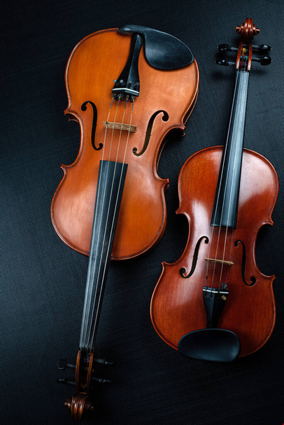 Hegedű és Viola fel a háttérben, mutatnak különböző méretű és részletességű akusztikus eszköz, fekete vászon háttér - Fotó, kép