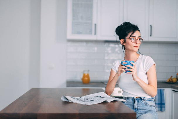 Beautiful young woman drinking coffee in the kitchen - Foto, afbeelding