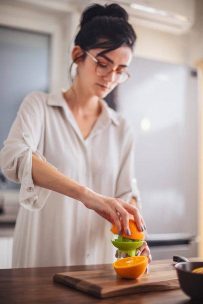 Woman making orange juice in the kitchen - Fotografie, Obrázek