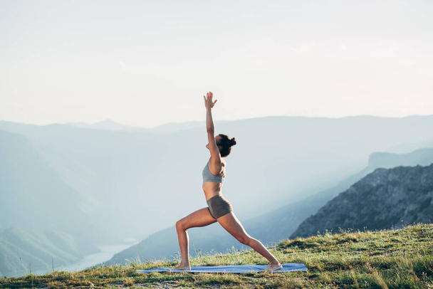 Fit young girl practicing yoga at sunset - Foto, Imagem