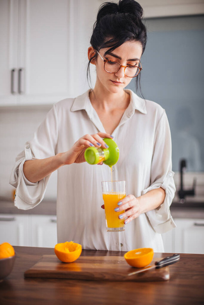Woman making orange juice in the kitchen - Foto, Imagen