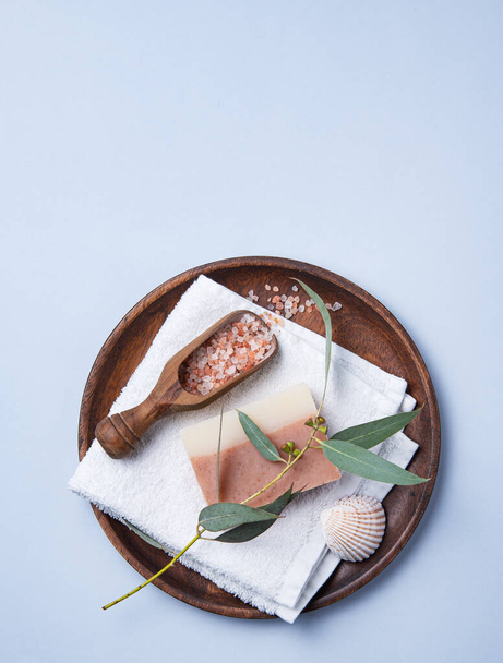 natural organic cosmetics with pink Himalayan salt, soap and eucalyptus branch on a blue  background. Aromatherapy and Spa treatments. Top view, flat lay and copy space - Photo, image