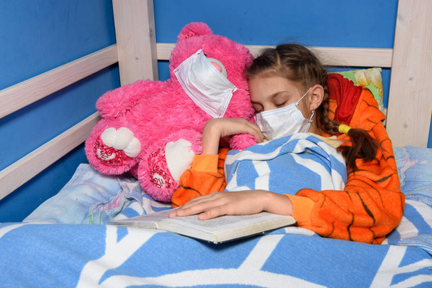 Άρρωστο κορίτσι με ιατρική μάσκα αποκοιμήθηκε στο κρεβάτι. - Φωτογραφία, εικόνα