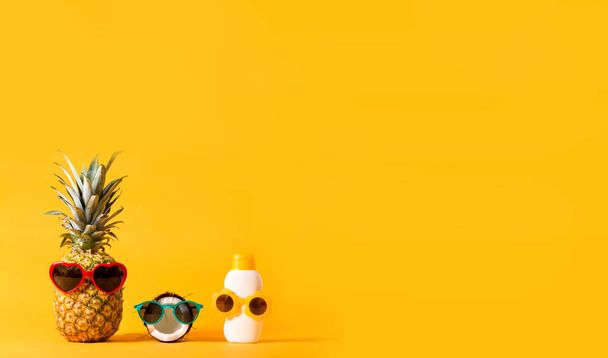 Pineapple and coconut wearing sunglasses with sunblock - Фото, зображення